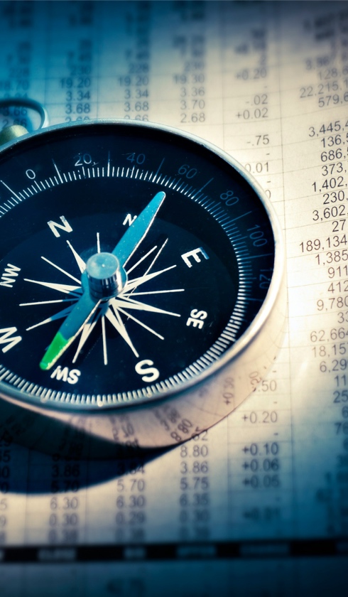 A close-up of a compass resting on a sheet filled with numbers and financial data, symbolizing direction in financial decision-making and precise damage calculations.