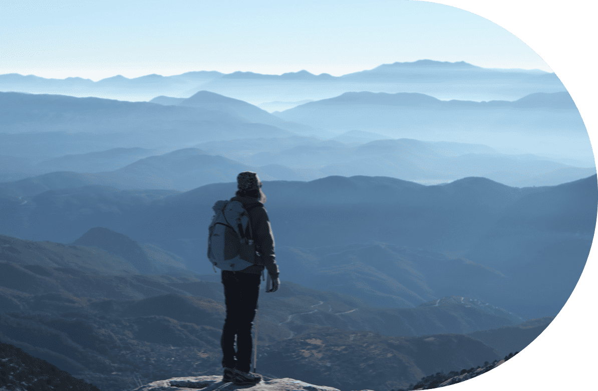 woman hiker standing on top mountain overlooking other mountain ranges