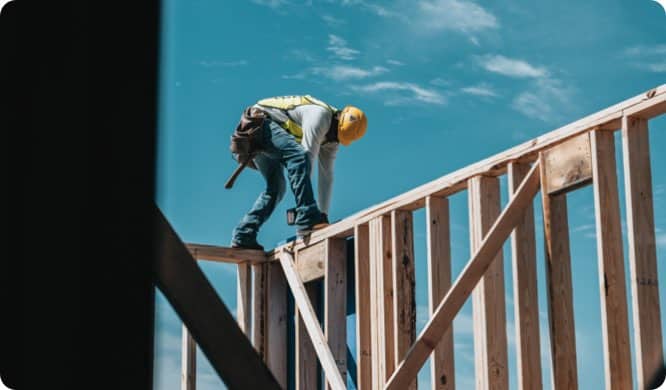house construction worker on wooden wall against blue sky