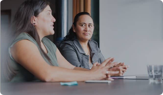 two maori women at a board room table