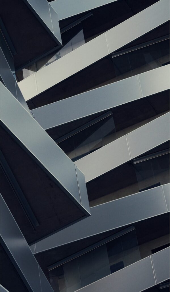 Close-up of a contemporary building façade with intersecting, angled steel beams layered over sleek glass panels. The geometric design forms an abstract architectural motif, visually symbolising meticulous programme design and execution.